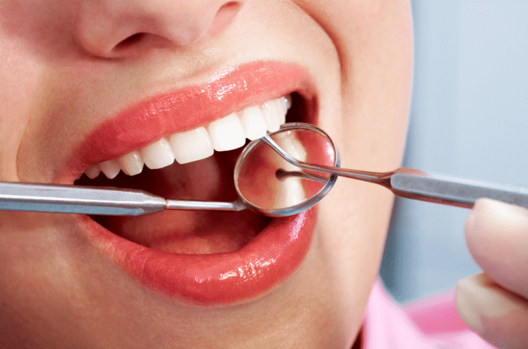 A dentist using a dental mirror to examine a patient's teeth during a routine checkup.