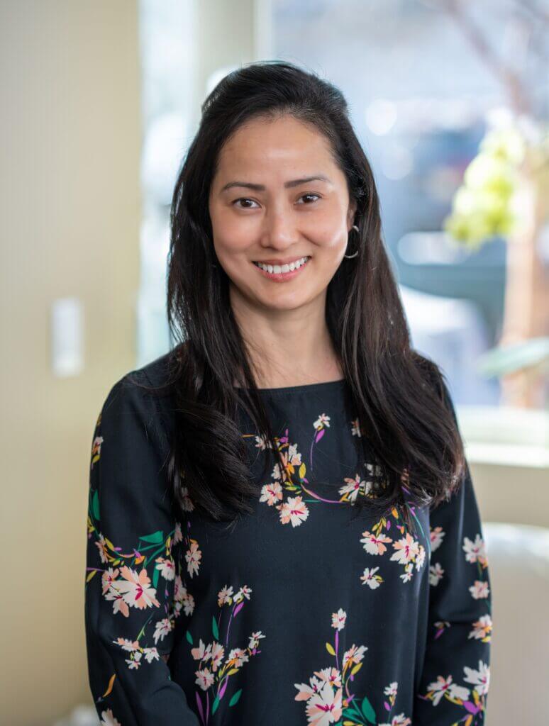 Smiling Asian woman in floral top.