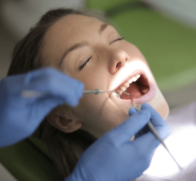 Dentist examining patient's open mouth.